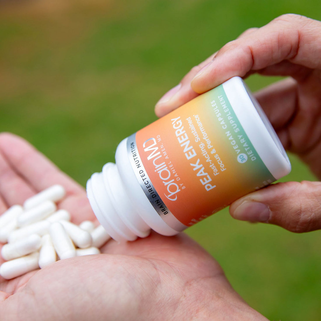 Hand pouring white capsules from a supplement bottle into a cupped palm
