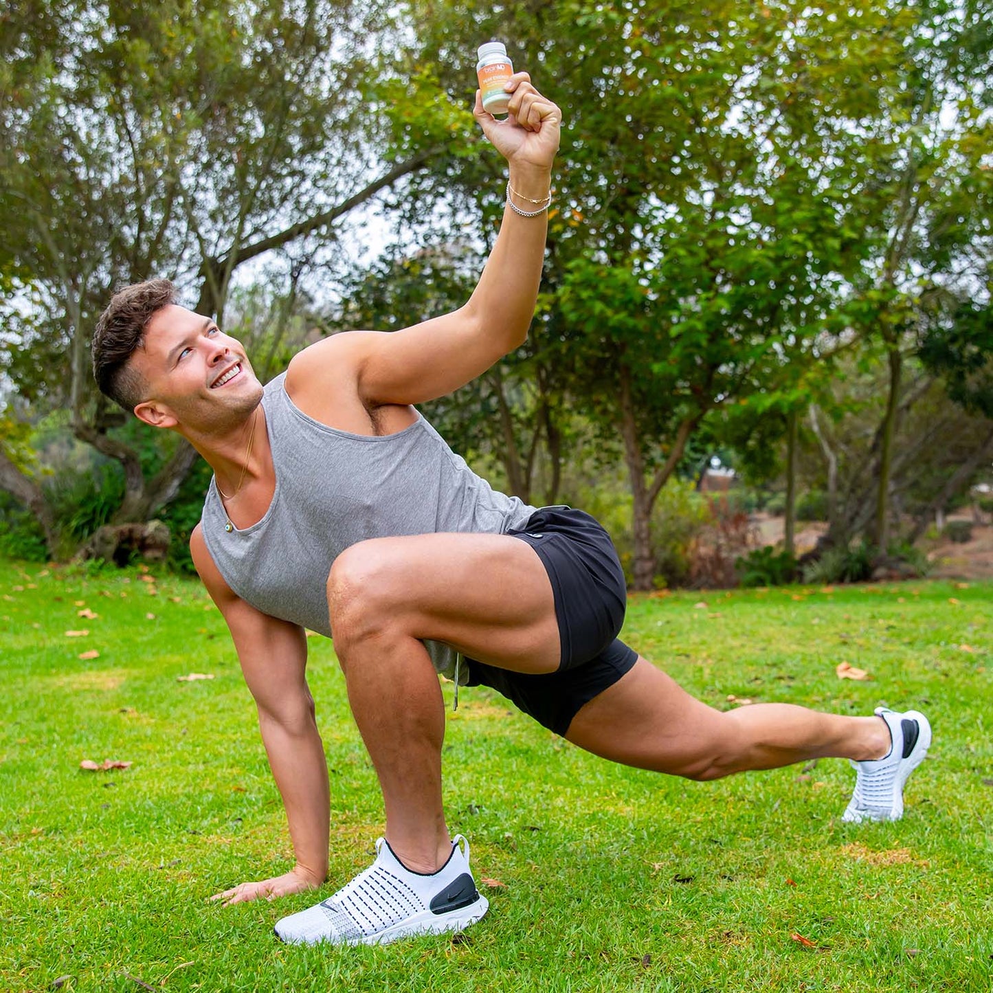 Man stretching in a park holding a bottle of Peak Energy ATP